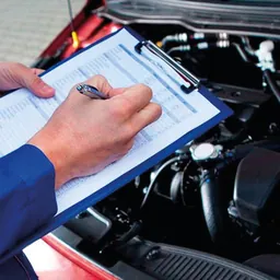 Técnico revisando el motor de un vehículo con su planilla